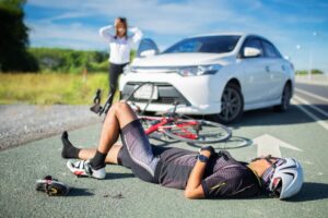 Unconscious male cyclist lying on the road after an accident, with selective focus.