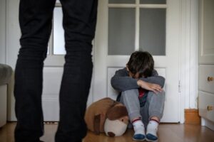 A view of a child victim of abuse, sitting alone in their room, conveying a sense of isolation and trauma.