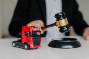 A male judge strikes a gavel on a block in a courtroom. Concept of prohibited export with a toy cargo truck placed on the table.