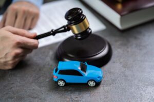 Small Red Car In Front Of Judge Holding Mallet