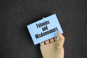 paper with the words Felonies and Misdemeanors. typically defined as a crime punishable by a term of imprisonment of one year or more.
