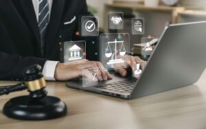 Hand of a lawyer on a laptop screen displaying a legal services icon, offering online legal advice in labor law for a business company, symbolizing the concept of a legal consultant and lawyer.