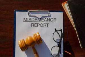 A clipboard holding a misdemeanor report rests on a desk, symbolizing the careful filing of non-felony criminal activity in legal proceedings.